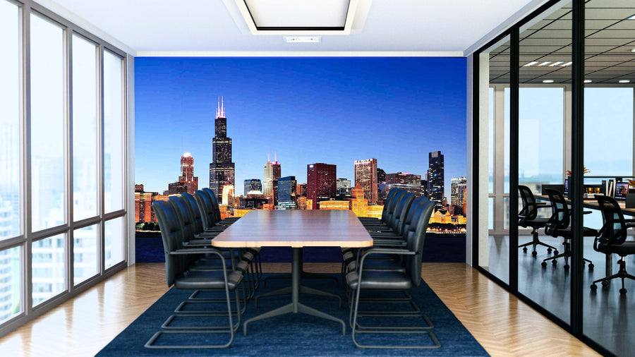 A modern conference room with a long table, black chairs, and a blue rug features floor-to-ceiling windows and a Chicago Night Panorama Wall Mural on the far wall, while glass walls reveal another office area next door.