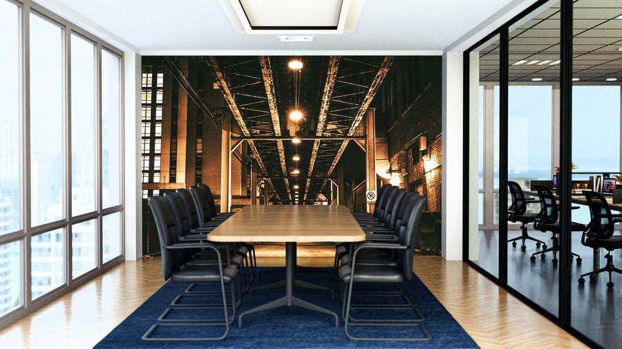 A modern conference room with a long wooden table, black chairs, and a dark blue rug. The back wall features the “Chicago Under the L Train Wall Mural.” Glass walls reveal city buildings and another office area.