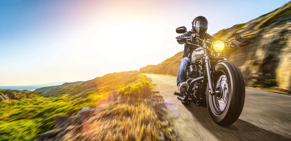 In the "Motor 26 Wall Mural," a motorcyclist in a black helmet rides a cruiser bike on a winding road, framed by rocky hills and lush greenery at sunset. The warm glow casts over the scene as the headlight brightens the path ahead, capturing the essence of adventure.