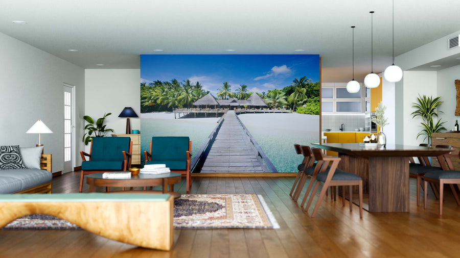 A modern, open-concept living and dining room with wood floors and mid-century furniture features the Coconut Palm Trees Wall Mural, displaying a tropical boardwalk to overwater bungalows and palm trees for a relaxing beach resort vibe.