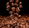 The Coffee Beans Falling Wall Mural features a close-up of glossy, textured coffee beans tumbling in mid-air against a dark background. A rich, aromatic pile forms at the bottom, creating an artful design with various shades of brown reminiscent of removable wallpaper.