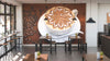 A modern café with wooden tables and stools, small potted plants on each table, pendant lights, and a large Coffee Beans Wall Mural featuring a cappuccino with latte art and coffee beans in the background.