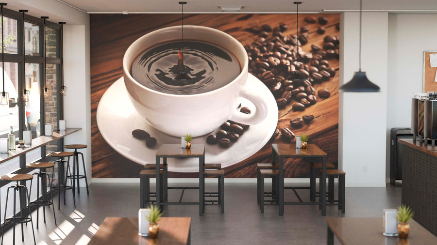 A modern café with wooden tables, stools, potted plant centerpieces, and large left-side windows. The back wall displays the Coffee Plant Wall Mural featuring a white coffee cup filled with coffee surrounded by coffee beans.
