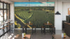 Modern café interior with wooden tables and chairs, potted plants on tables, large windows on the left, and a wall-sized Coffee Rows Wall Mural depicting a lush green vineyard under blue sky. Pendant lights illuminate cozy seating.
