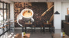A modern coffee shop interior features wooden tables, black chairs, plants, hanging lights, and the Fresh Coffee Beans Wall Mural. Large windows along the left wall fill the cozy space with natural light.