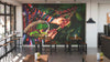 A modern café showcases wooden tables, stools, lush green plants, and a Handpicked Coffee Berries Wall Mural on the back wall. Large windows on the left fill the space with natural light.