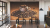 A modern café interior features wooden tables and stools, small plants on each table, and the Overflowing Coffee Beans Wall Mural—a striking design with a white coffee cup surrounded by coffee beans. Pendant lights and large windows complete the look.