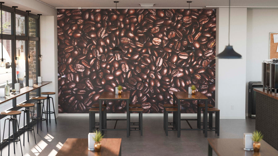 A modern café interior features wooden tables, stools, potted plants, and the Rich Coffee Beans Wall Mural covering the back wall. Pendant lights hang above, while large left-side windows flood the space with natural light.