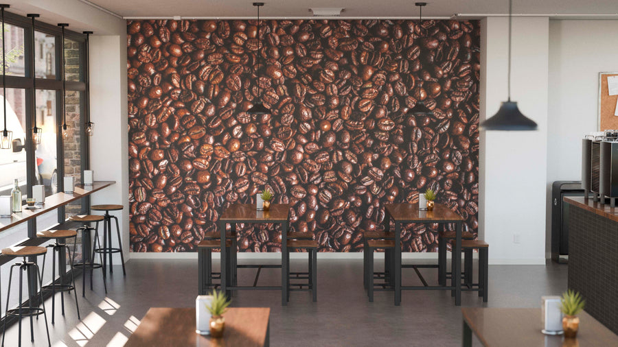 A modern café features wooden tables, stools, and small potted plants. The "Rich and Aromatic Wall Mural" showcases a close-up of glossy coffee beans. Pendant lights hang overhead, while large windows fill the space with natural light.