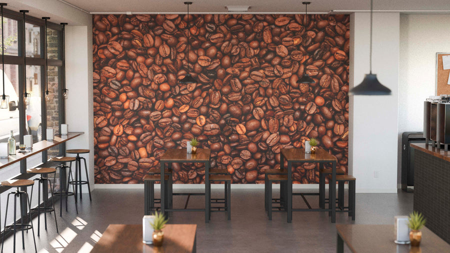 A modern café with wooden tables and stools, small potted plants on each table, and a Roasted Roots Wall Mural featuring close-up coffee beans. Pendant lights hang overhead while natural light pours in through large windows on the left.