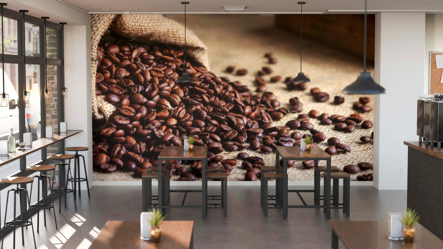 Modern café interior with high tables, stools, small plants, and large windows for natural light. The main wall features the Spilled Beans Wall Mural, showcasing coffee beans spilling from a burlap sack and adding warmth to the space.