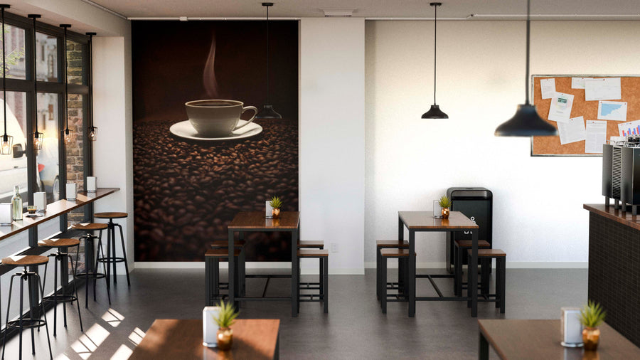 A modern coffee shop with wooden tables and chairs, small potted plants, a Steaming Coffee and Beans Wall Mural, windows on the left, a corkboard with papers, and pendant lights hanging above.