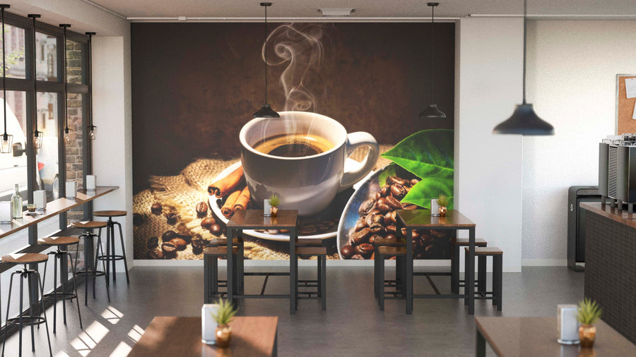 A modern, bright café with wooden tables and stools features a Warm Coffee Aesthetic Wall Mural depicting steaming coffee, beans, cinnamon sticks, and green leaves. Pendant lights hang above, plants accent tables, and large windows line one wall.