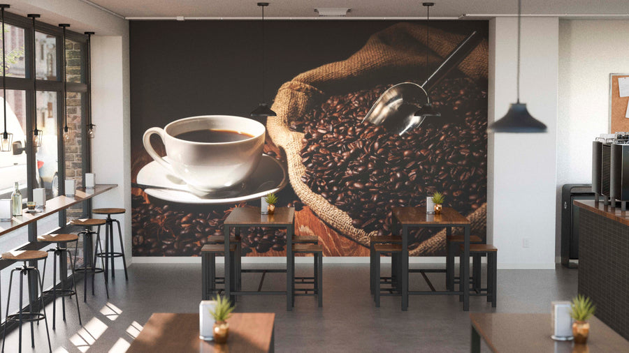 A modern coffee shop with wooden tables and stools, small potted plants, and the Warm Coffee with Beans Wall Mural. Pendant lights hang above, while windows line the left side.
