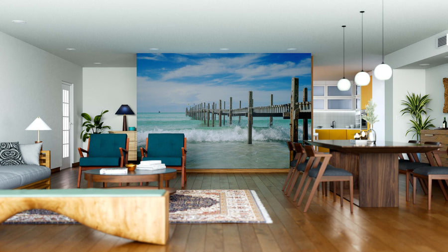 A modern open-plan living and dining room features mid-century furniture, wood accents, and the Crashing Waves Wall Mural, a peel and stick design that brings breezy coastal vibes and is easy to update with removable wallpaper.