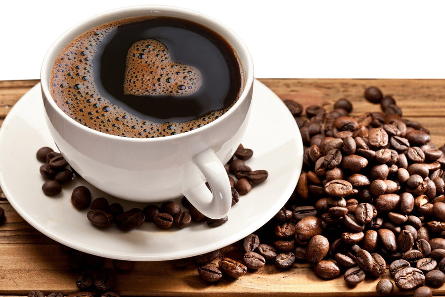 A bright, modern coffee shop with wooden tables and potted plants features the "Cup Full of Coffee Beans Wall Mural"—a peel and stick mural showcasing a coffee cup with heart-shaped foam and beans, adding warmth and charm to the space.