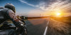 A motorcyclist in black gear speeds down a road at sunset, evoking the dynamic imagery of the Endless Open Road Wall Mural. The blurred background heightens the speed effect, while the warm landscape glow echoes custom printed murals.