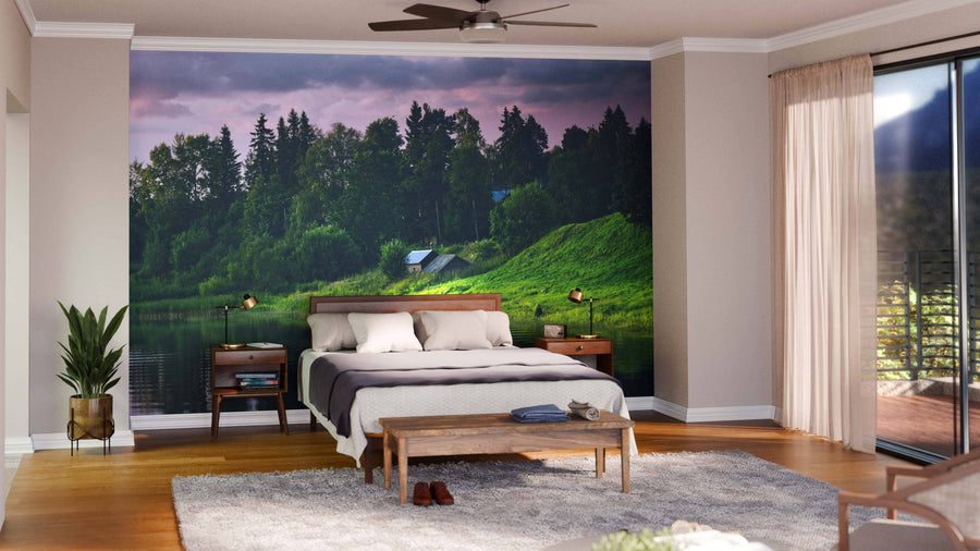 A modern bedroom features a bed with white bedding, wooden headboard, and benches. Behind it, the Fairy Houses Near River Wall Mural adds charm. Large windows with sheer curtains let in light, while plants enhance the cozy atmosphere.