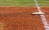 Bright and vibrant, the First Base Wall Mural features a close-up of first base on reddish-brown dirt with a white chalk foul line and green grass—a sunlit scene perfect for personalized decor in peel-and-stick format.