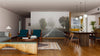 A modern living and dining area features wooden floors, a mix of upholstered and wood furniture, pendant lights over the table, cozy rugs, art accents, and a stunning Foggy Road Wall Mural depicting a misty road with trees.