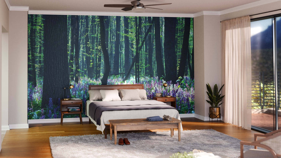 A modern bedroom features the Forest Landscape with Spring Flowers Wall Mural behind the bed, complemented by wooden furniture, potted plants, hardwood floors, and natural light for a serene atmosphere.