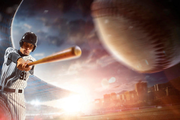 The Baseball 14 Wall Mural shows a baseball player in a black helmet and striped uniform swinging a bat, with a large baseball flying forward, stadium seats, and a city skyline blurred in the sunset background.