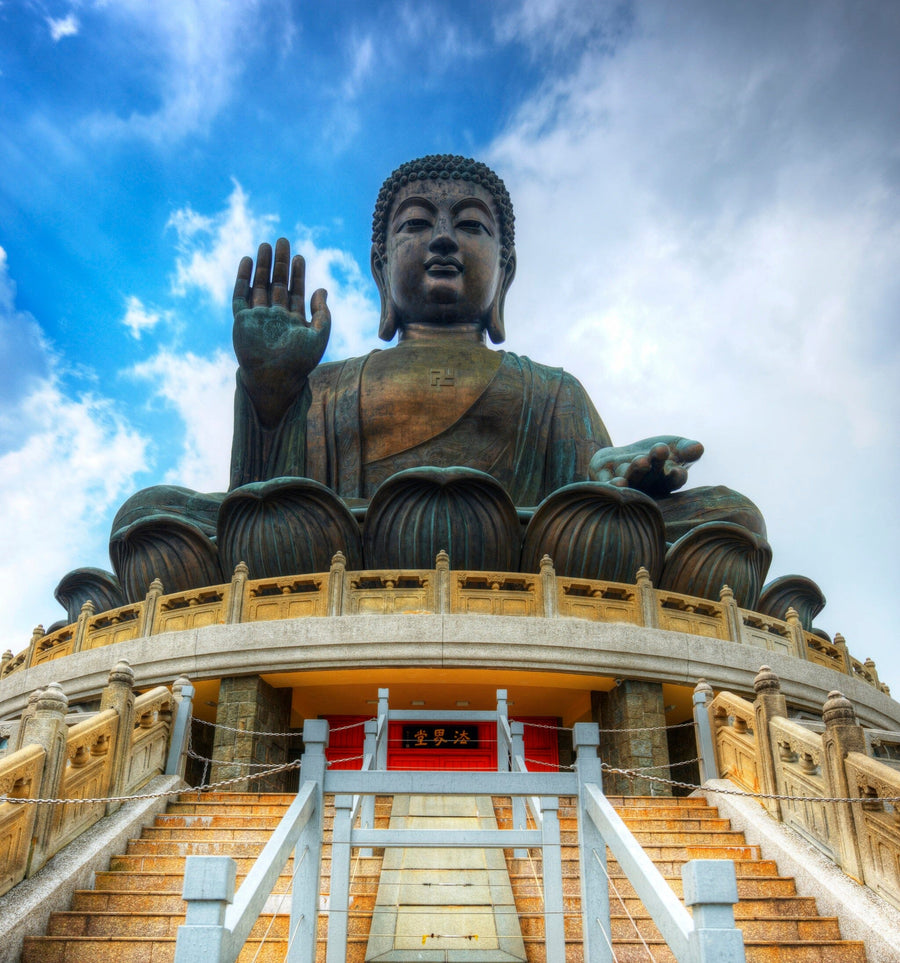 Modern living-dining room with wooden floors, chic furniture, and globe pendant lights features the Giant Buddha of Hong Kong Wall Mural, showcasing a majestic outdoor Buddha statue beneath a blue sky for a serene, cultural accent.