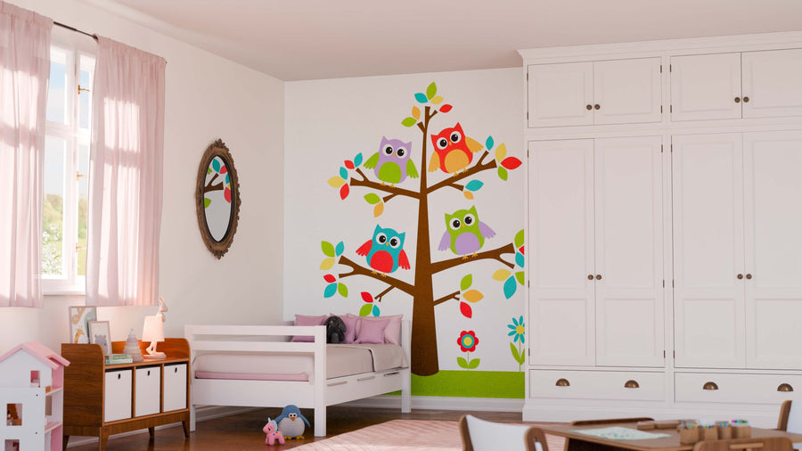 A child’s bedroom featuring pink curtains, a white bed with pink bedding, and a wooden side table. The Playful Owl Family Tree Wall Mural adds colorful charm and easy style with its cartoon owls and flowers on the wall.