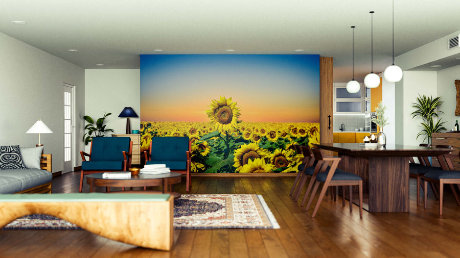 A modern living-dining area features wood floors and mid-century furniture. The Golden Field Glow Wall Mural adds vibrant sunset sunflowers, while plants, pendant lights, and a patterned rug complete the stylish, inviting space.