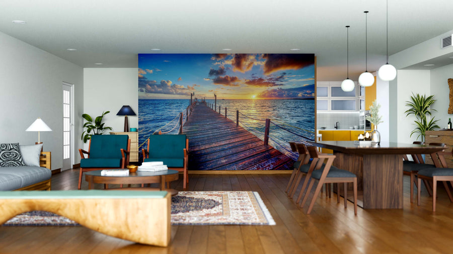 Modern living-dining room with wood floors, stylish furniture, pendant lights, and the Golden Ocean View Wall Mural—a peel and stick mural featuring a wooden pier at sunset with dramatic clouds and vibrant colors for a relaxing vibe.
