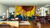 A modern open-concept living and dining room features wood floors, blue chairs, and a dark table. The Golden Petals Wall Mural covers the back wall, providing a vibrant sunflower focal point that energizes the space.