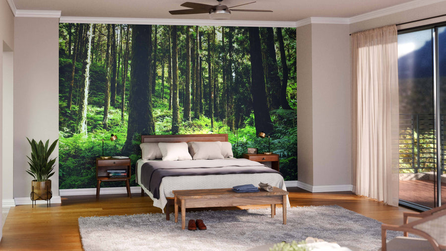 Modern living and dining room with wood floors, teal armchairs, a Green Forest of Alishan Wall Mural, dark wood dining table, pendant lights, rugs, and a kitchen in the background featuring yellow accents and white cabinetry.