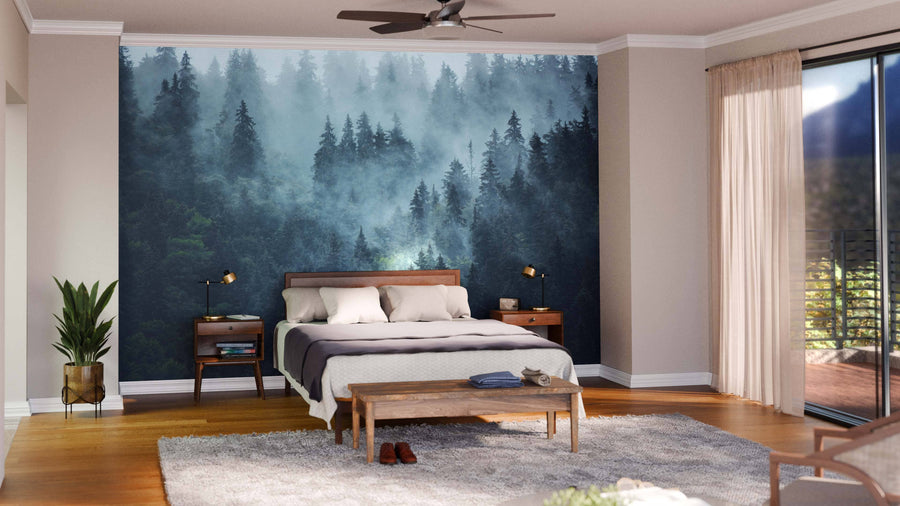 Modern bedroom featuring the Green Misty Mountain Landscape Wall Mural behind the bed, wooden furniture, a gray rug, and a plant in the corner. Natural light fills the space through floor-to-ceiling windows with sheer beige curtains and balcony views.