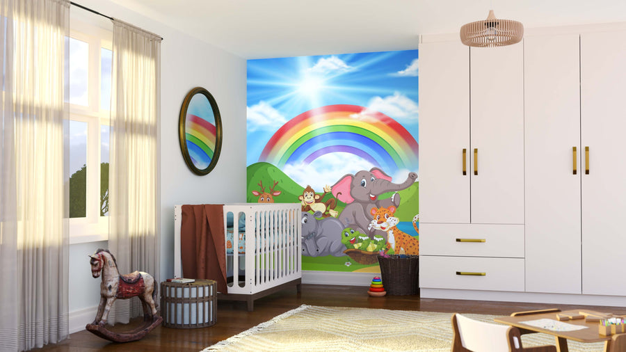 A bright nursery with a crib, rocking horse, and wardrobe features the Happy Animal Valley Wall Mural behind the crib, showing cartoon jungle animals under a rainbow in a sunny green landscape with blue sky and clouds.