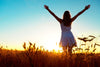 A silhouetted woman in a white dress, arms raised, faces the sunrise in a wheat field, evoking the tranquility of the Inspirational 5 Wall Mural. The golden wheat against the warm hue sky creates a serene and uplifting atmosphere.