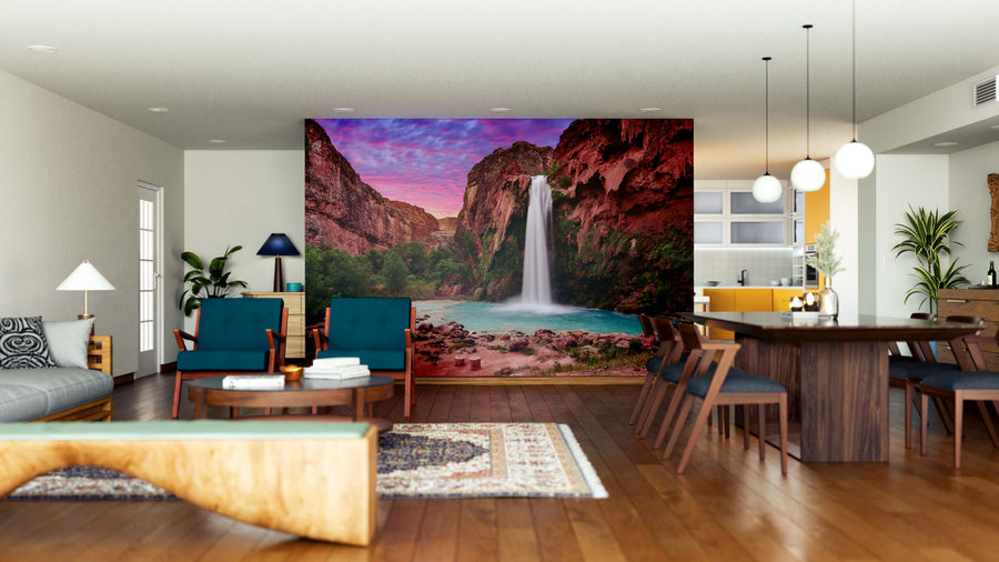 Modern open living-dining area with wooden floors, eclectic furniture, and a large Havasu Falls in Havasupai Wall Mural depicting a scenic canyon waterfall at sunset as a striking natural focal point framed by red cliffs.