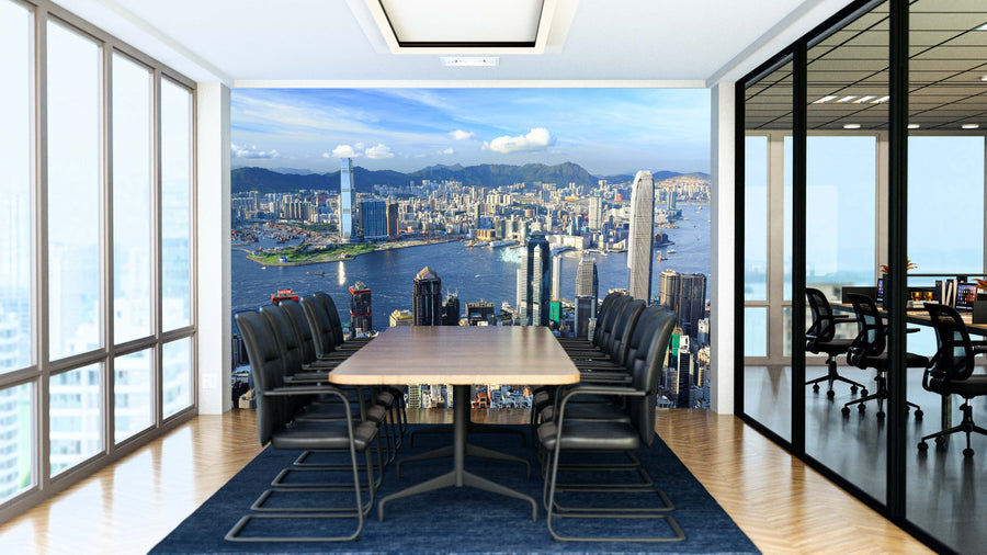 A modern conference room with a wooden table, black chairs, and floor-to-ceiling windows features the Hong Kong Wall Mural depicting a city skyline and harbor. Glass walls separate it from another office with desks and chairs.