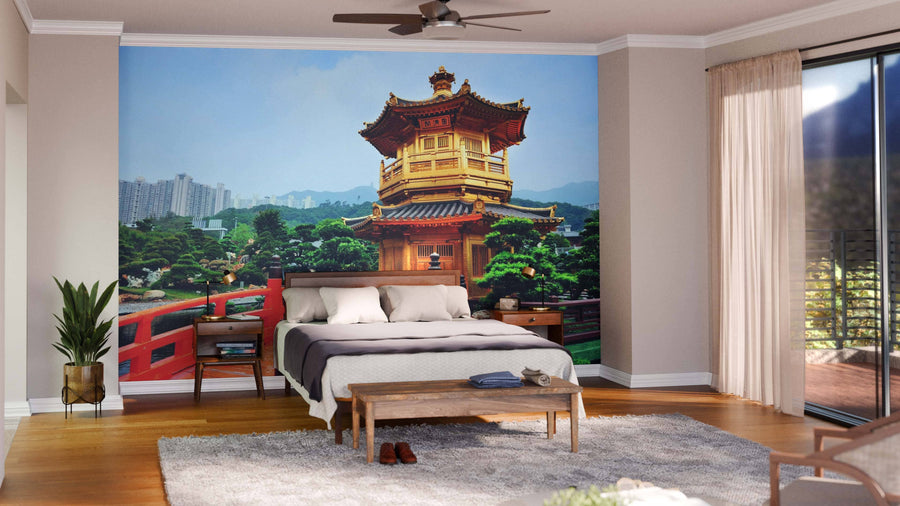 A modern living-dining room with wooden floors, teal armchairs, and a Hong Kong Garden Wall Mural depicting a traditional Asian pagoda, red bridge, and lush greenery. The dining area has a dark table, chairs, and globe pendant lights.