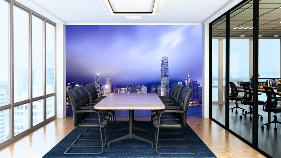 A modern conference room with a long table, black chairs, and glass walls. The far wall displays the Hong Kong at Night Wall Mural, featuring illuminated skyscrapers at dusk. Adjacent room is visible through the glass partition.