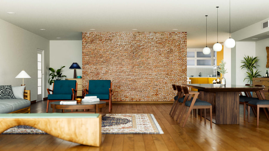 A modern open-concept living and dining area features wood flooring, a Huge Brick Wall Mural, blue armchairs, a gray sofa, a rug, a large wooden dining table with chairs, pendant lights, and a kitchen with yellow cabinets in the background.