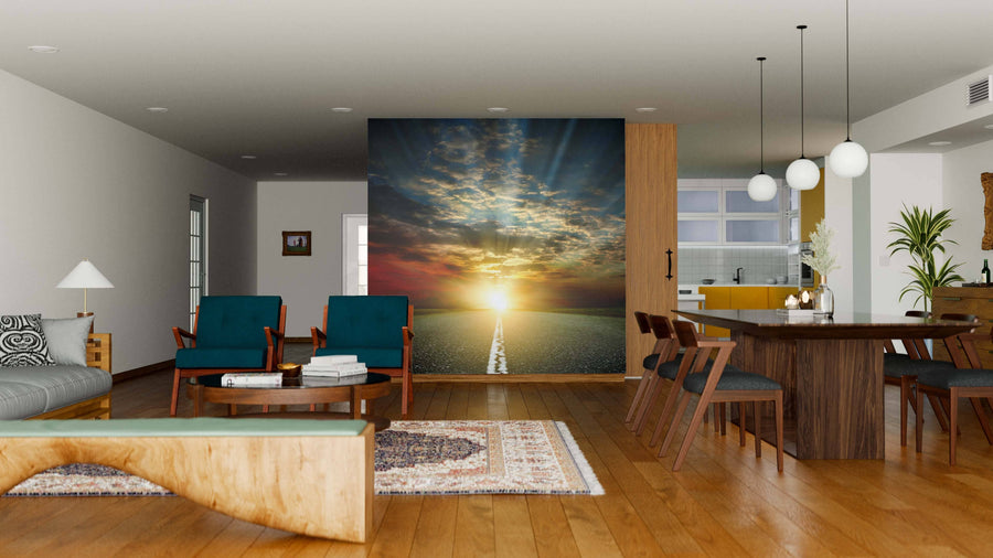A modern, open-plan living and dining room with wooden floors, blue and wood furniture, pendant lights, and the Asphalt Road and Sunset Wall Mural as a striking peel-and-stick accent. The kitchen area appears in the background.