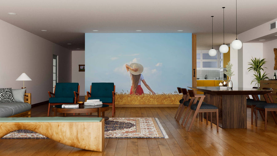 A modern open living-dining area with wood floors, teal chairs, a wooden dining table, a large screen, and pendant lights is enhanced by the Beneath Open Skies Wall Mural. The kitchen can also be seen in the background.