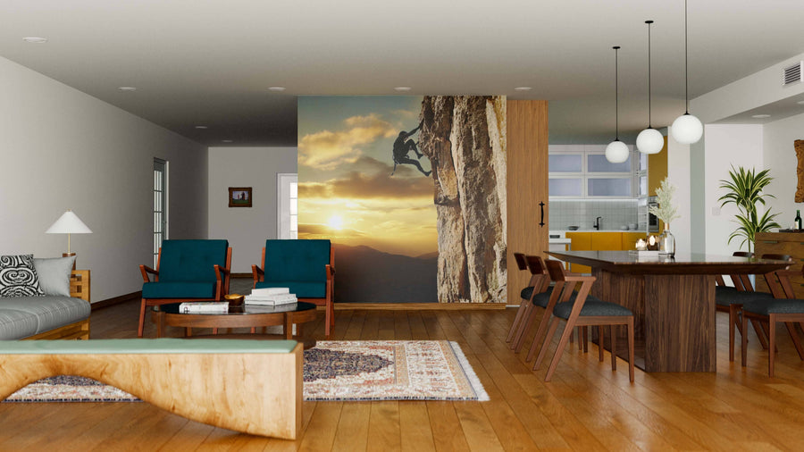 A modern, open-concept living and dining room with wood floors and mid-century furniture features the Climber on Sunset Wall Mural, adding a dramatic focal point of a rock climber at sunset between the living and kitchen areas.