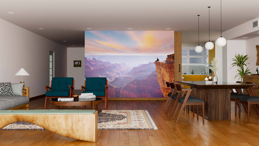 A modern living-dining room with wood flooring, teal and wood chairs, a sofa, and pendant lights. The back wall showcases the Edge of Infinity Wall Mural, depicting the Grand Canyon at sunset and adding vibrant color to the space.