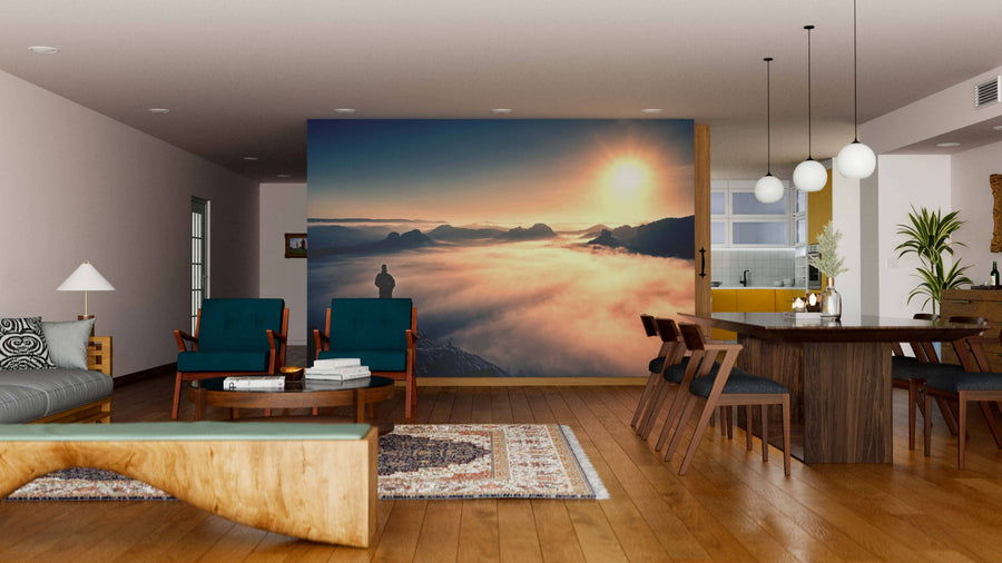 Modern living and dining room with wooden floors and furniture. The wall showcases the Peak of Sandstone Rock Wall Mural, depicting a scenic sunrise over mountains. Contemporary lighting, accent chairs, and removable wallpaper complete the space.