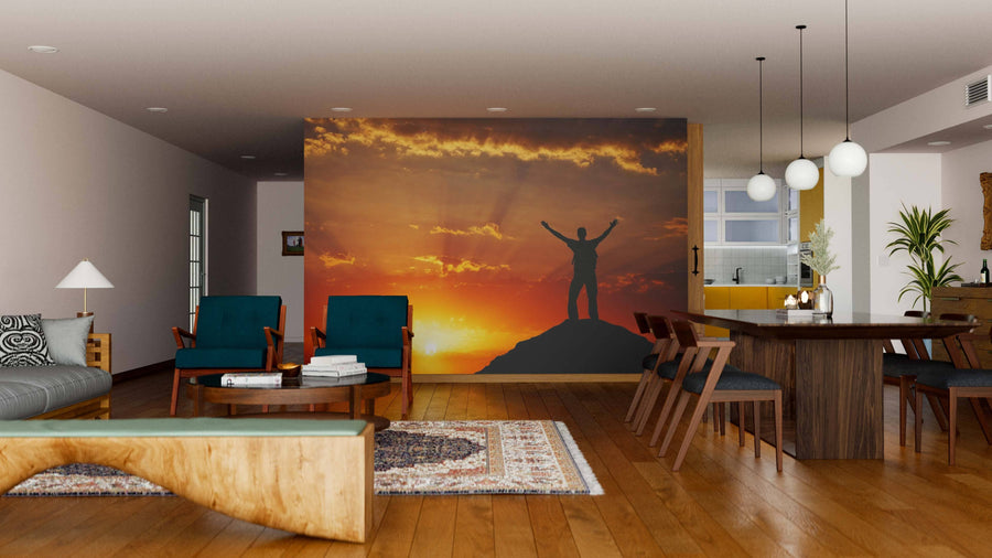 Modern living and dining area with wooden floors and mid-century furniture features the Silhouette of a Man Wall Mural, showing a figure atop a mountain at sunset as an inspiring focal point in the room.