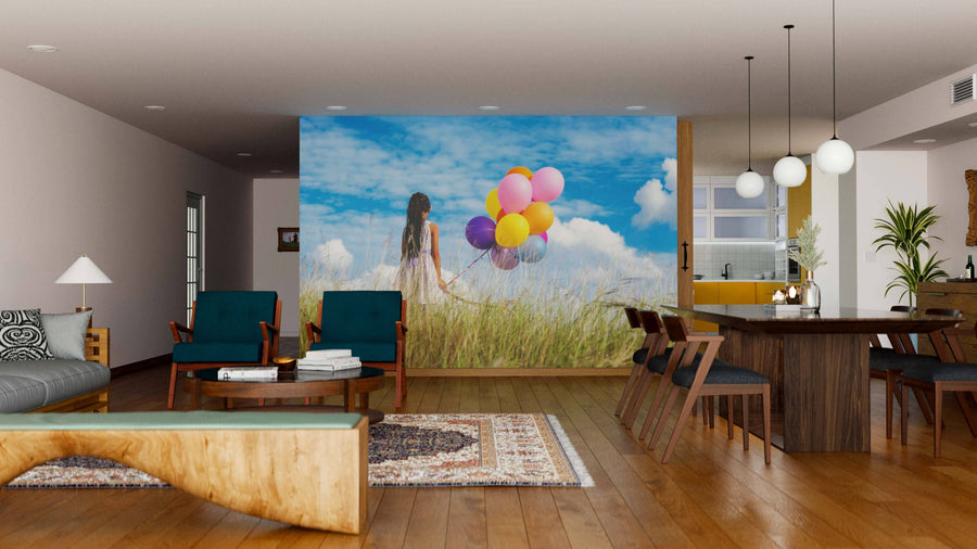 A modern living-dining room with wooden floors and contemporary furniture features the Skybound Dreams Wall Mural—a vibrant image of a woman holding colorful balloons in a grassy field—adding a whimsical focal point to the space.