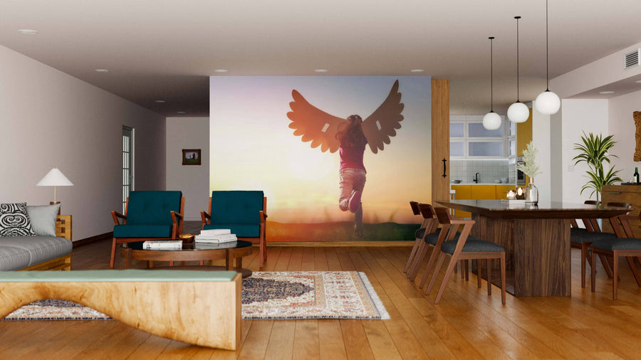 A bright, open living-dining area with wooden floors, teal armchairs, a wooden table, pendant lights, and the Wings Wall Mural depicting a child with wings at sunset creates warmth and charm in the space.