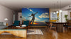 Modern living-dining room with wooden floors, mid-century furnishings, and the "Woman Embracing Freedom Wall Mural" featuring a joyful silhouette against a vibrant sunset. Warm, inviting atmosphere with contemporary decor.