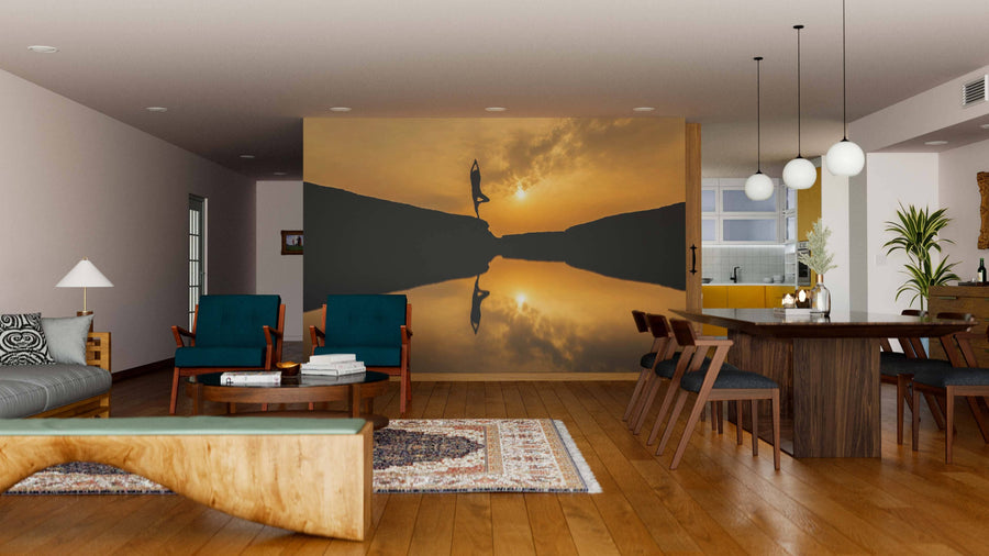 A modern living-dining room with wooden floors, stylish furniture, and a large Yoga Pose Wall Mural showing a person doing a handstand at sunset by a reflective lake. Round pendant lights hang above a wooden dining table for six.